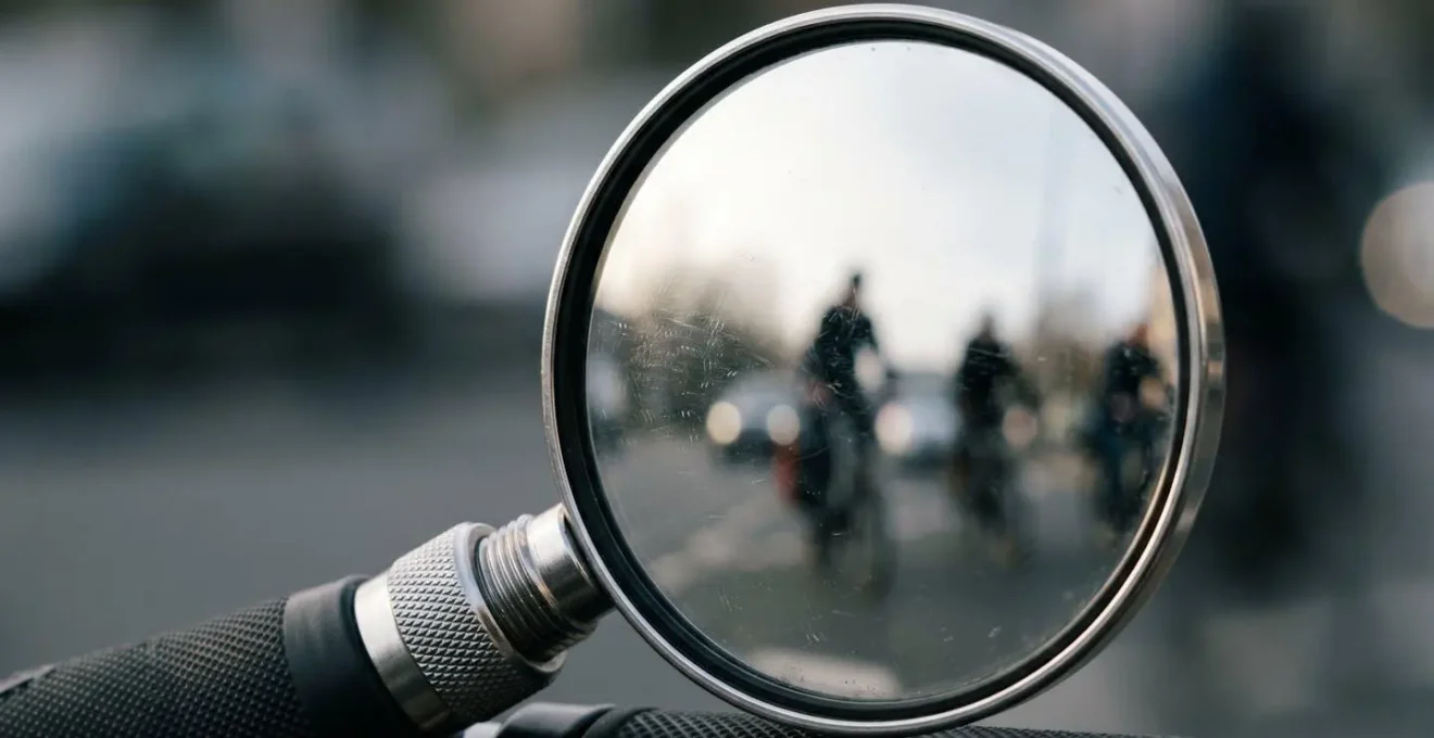 Rétroviseur de vélo monté sur guidon montrant le reflet d'un cycliste et de la circulation en arrière-plan